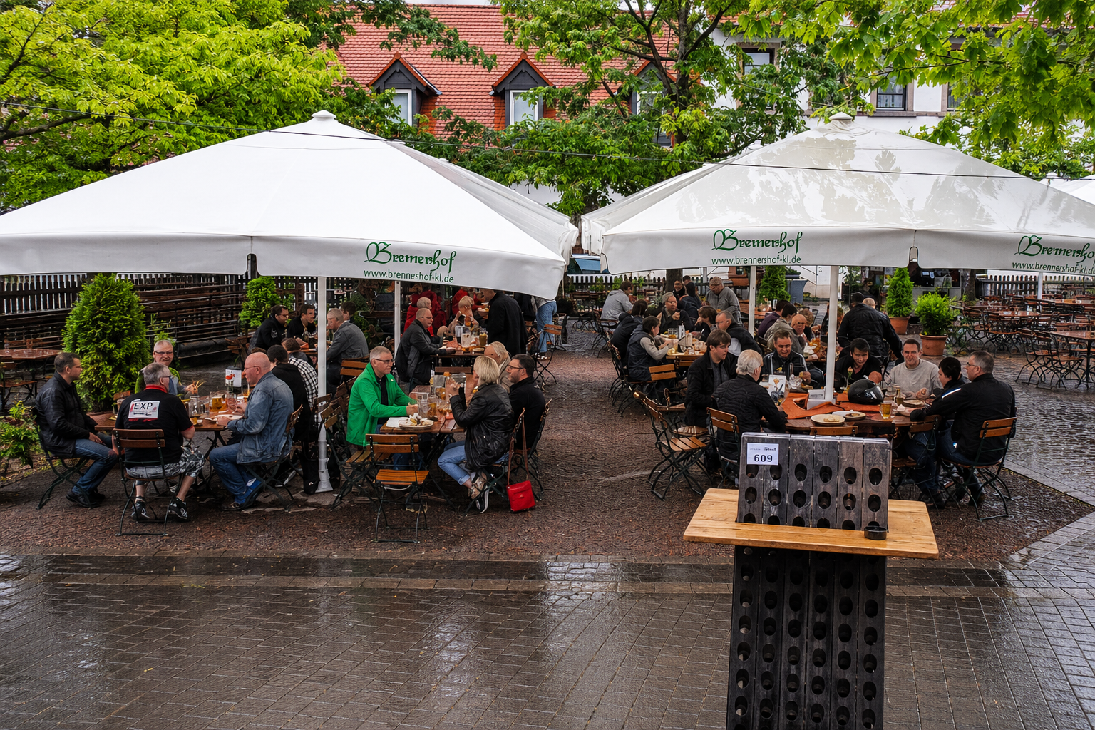 Gäste beim R+V Sommerfest unter Schirmen bei regnerischem Wetter